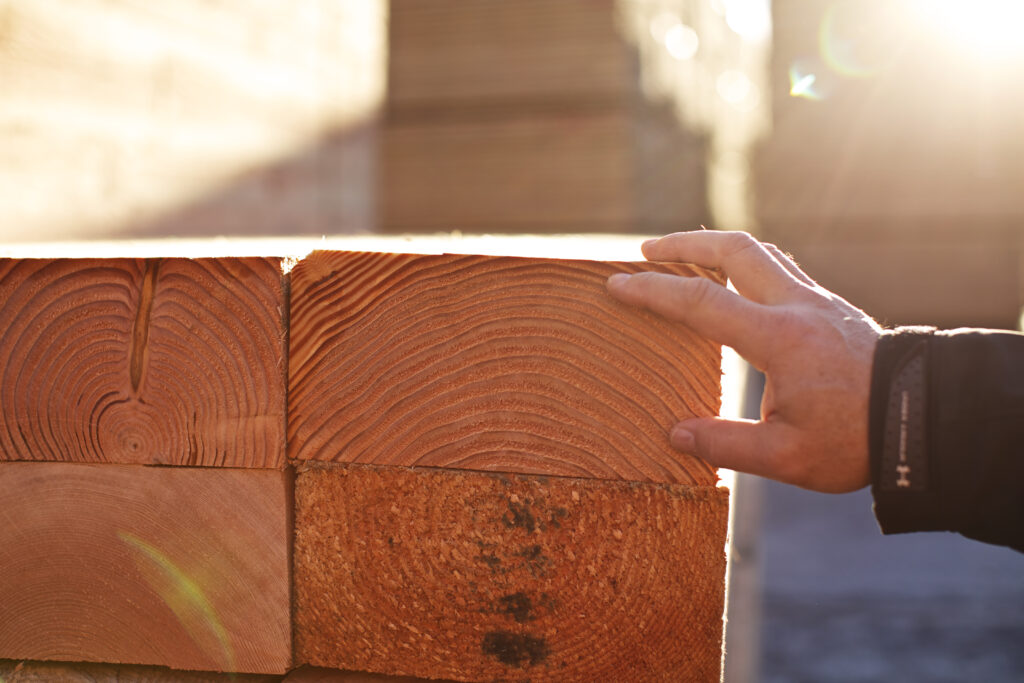 A persons hand touching a large pile of lumber