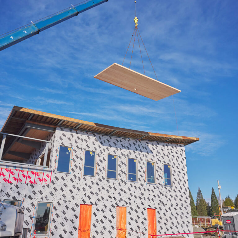 A crane lifting wood during the construction of Marpole Community Centre